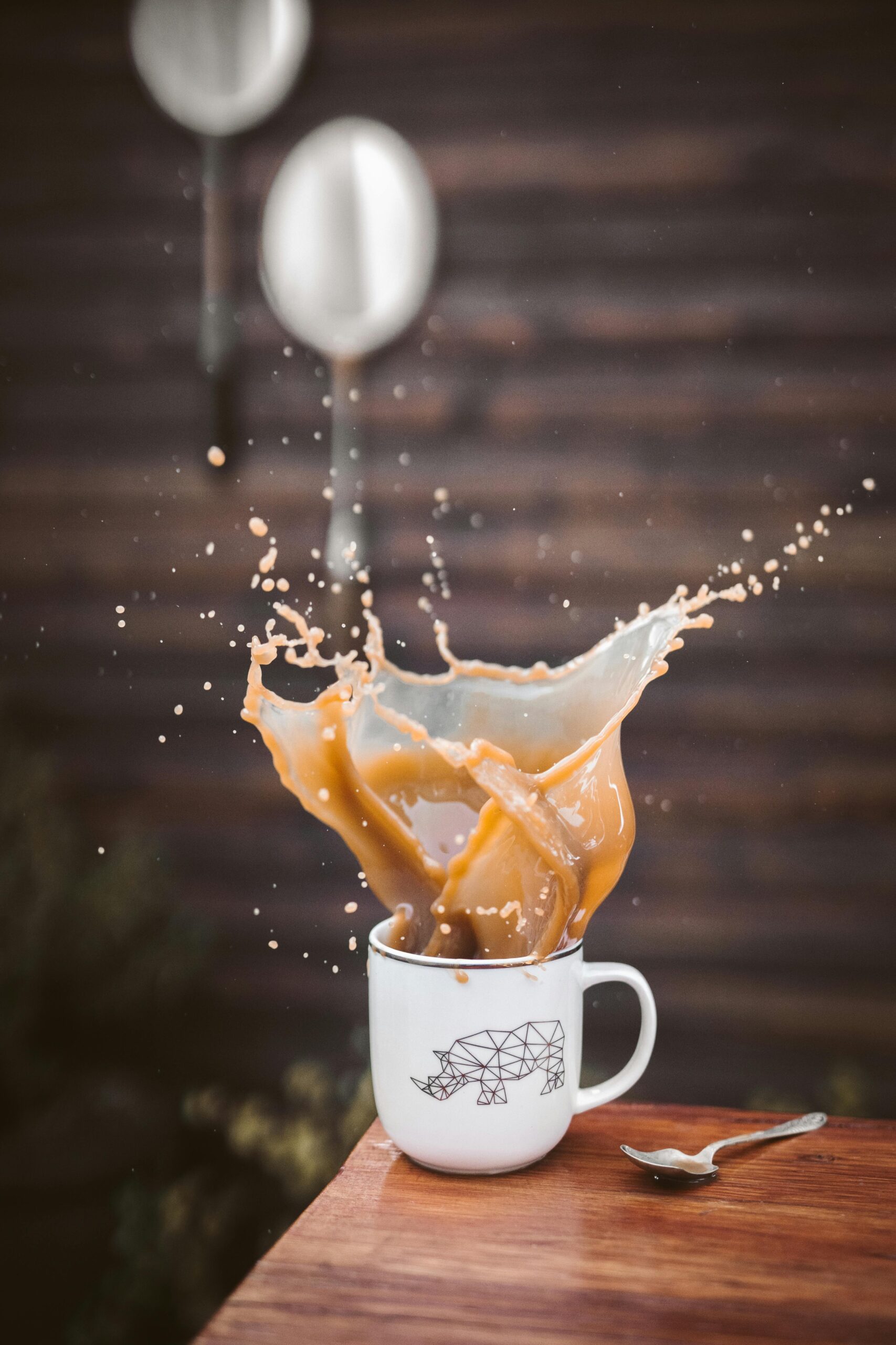 Capture of a vibrant coffee splash in a white mug with geometric bear design, evoking energy and movement.